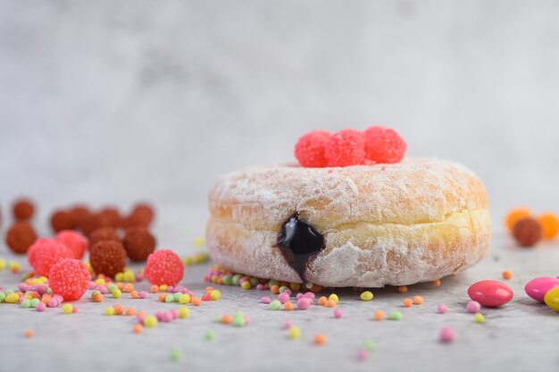 Donuts sprinkled with icing sugar and candy on a white surface.