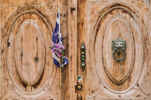 Foto gratuita la porta di una vecchia casa decorata con la bandiera della grecia e una corona di protomaya la città di rodi un viaggio nei luoghi popolari dell'arcipelago del dodecaneso grecia