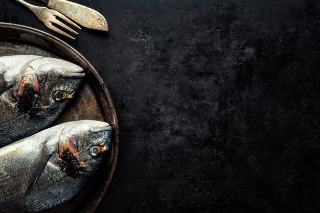 Рыба дорадо с ингредиентами на темном