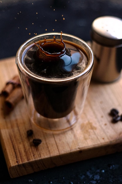 Double espresso coffee mug with cinnamon sticks and coffee beans on a wooden board