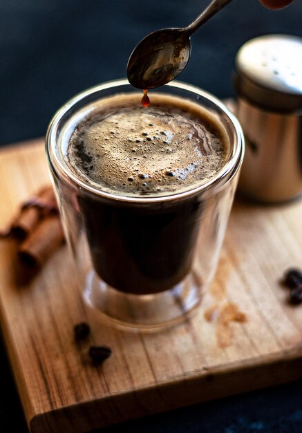 Double espresso coffee mug with cinnamon sticks and coffee beans on a wooden board