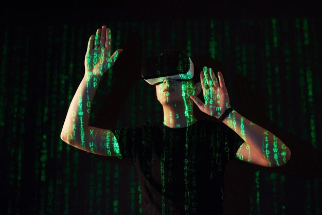 double exposure of a caucasian man and virtual reality vr headset is presumably a gamer or a hacker cracking the code into a secure network or server, with lines of code in green