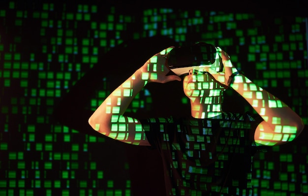 Foto gratuita la doppia esposizione di un uomo caucasico e un visore vr per realtà virtuale è presumibilmente un giocatore o un hacker che inserisce il codice in una rete o server sicuro, con righe di codice in verde