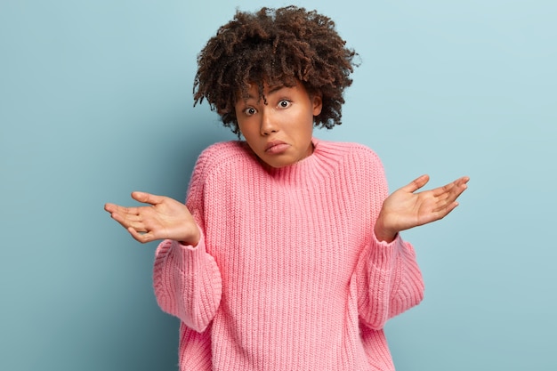 Foto gratuita la donna afroamericana dubbiosa allarga le mani, si sente insicura, affronta argomenti non familiari, si sente perplessa mentre cerca di trovare una risposta