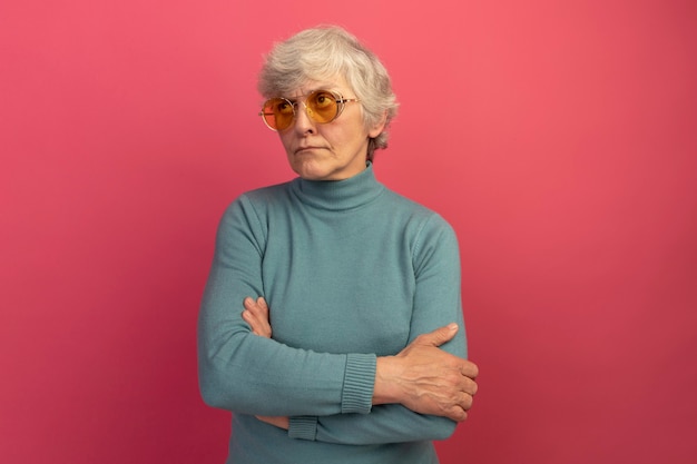 Free photo doubtful old woman wearing blue turtleneck sweater and sunglasses