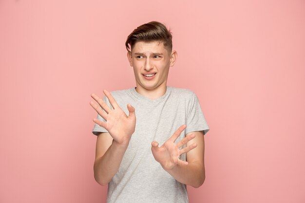 Doubtful pensive man with thoughtful expression making choice against pink wall