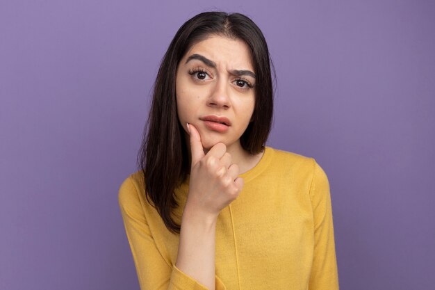 Doubtful young pretty caucasian girl keeping hand on chin 