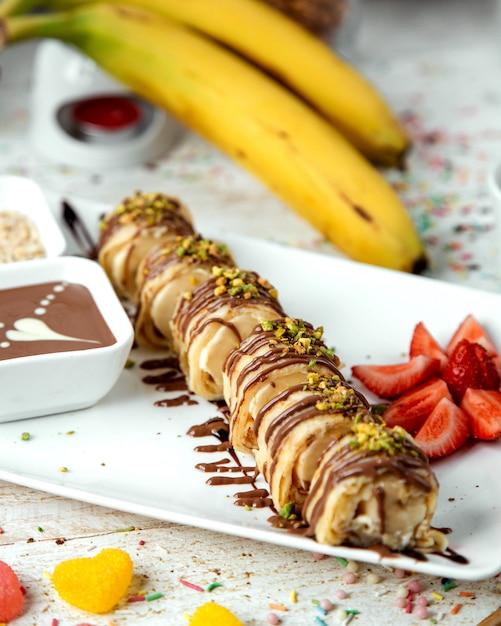 Dough banana coated with chocolate syrup and grated pistachios