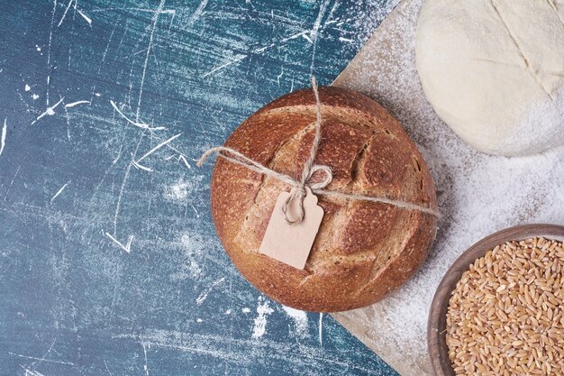 Dough and cooked bread on blue table.