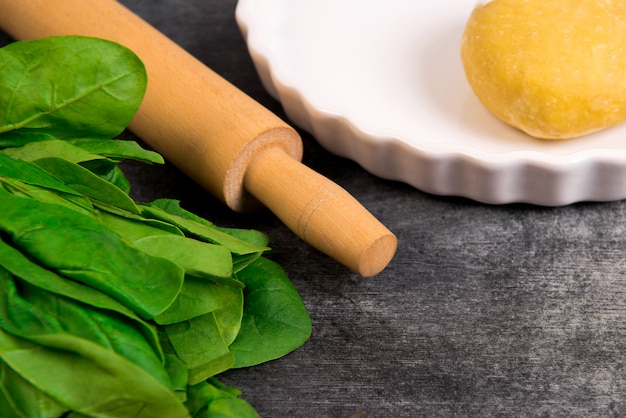 Dough and greens on grey wooden table