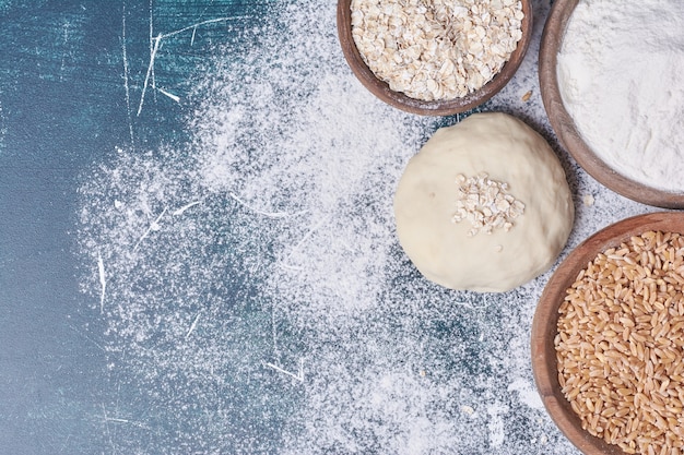 Dough and ingredients on blue table.