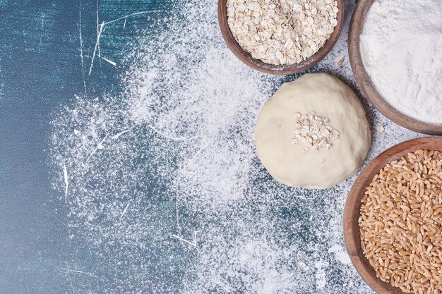 Dough and ingredients on blue table.