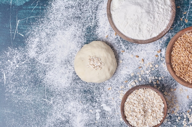 Dough and ingredients on blue table.