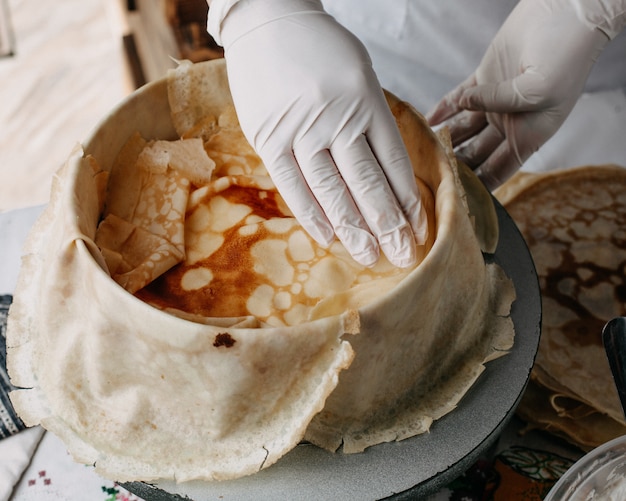 Free photo dough inside round pan with cook spreading pieces on it inside kitchen