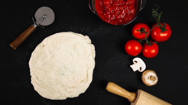 Dough near vegetables and kitchenware