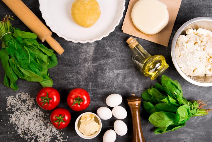 Free Photo dough, oil, cheese, tomatoes, eggs, greens over grey wooden surface