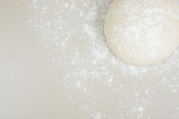 Dough powdered with flour on white table.