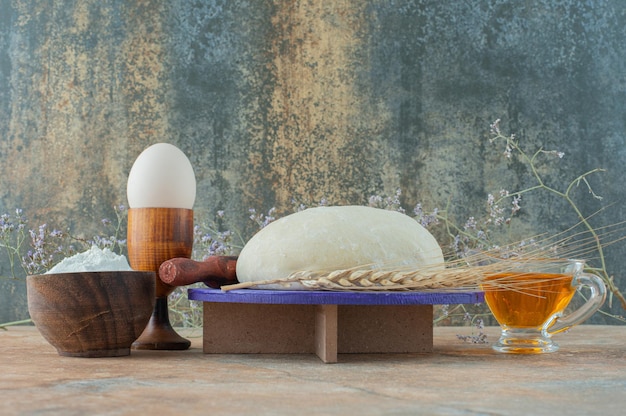 Тесто со скалкой и яйцом на мраморном столе.