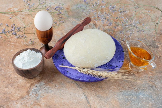 Dough with rolling pin and egg on marble