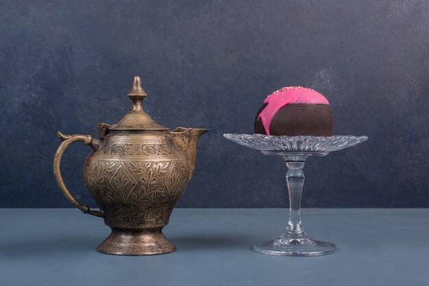 Doughnut on glass plate with ancient kettle .