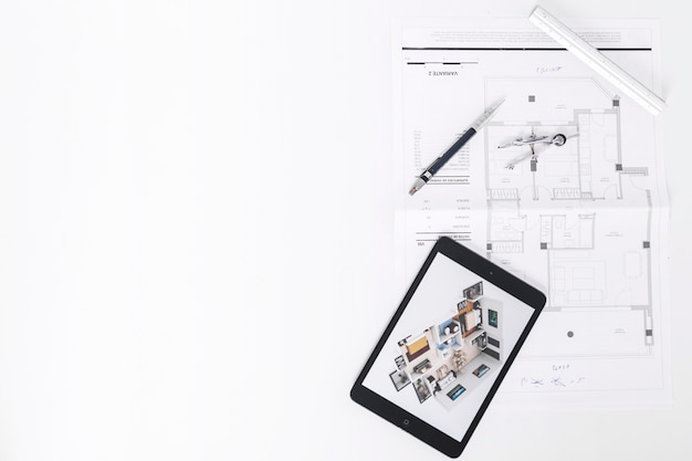 Drafting tools near tablet and blueprints