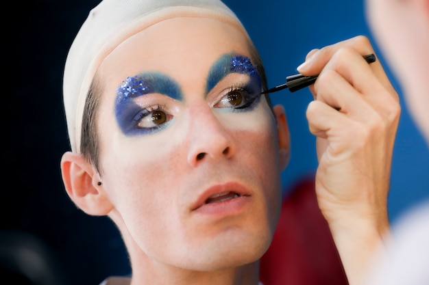 Free photo drag person putting on makeup