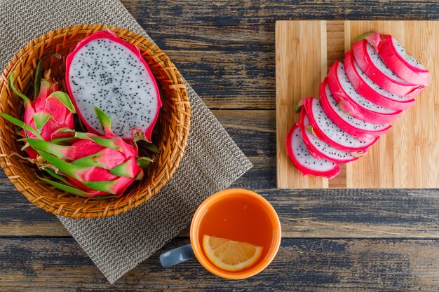 Dragon fruit in a basket with placemat, tea flat lay on wooden and cutting board