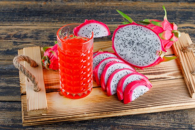 Dragon fruit in a tray with juice high angle view on a wooden table