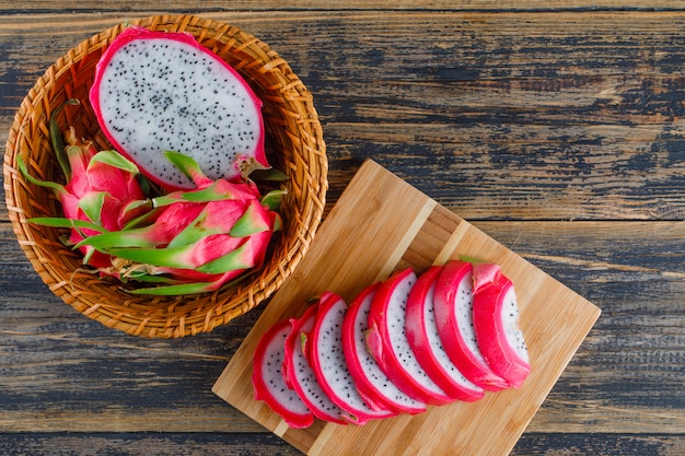 Dragon fruit in a wicker basket on wooden and cutting board. flat lay.