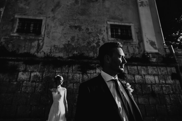 石の壁の前にポーズを取る結婚式のカップルの劇的な黒と白の写真