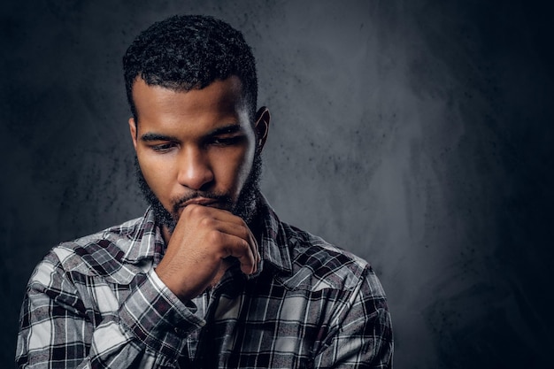 Dramatic portrait of Black pensive male over dark grey background.