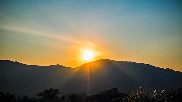 Драматический закат или восход солнца с бликами на фоне красивой природы горной долины.