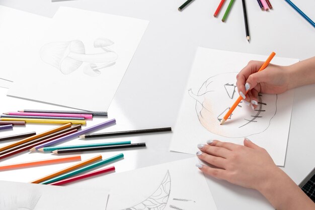 Drawing a young girl hand drawing a halloween pumpkin with orange pencil