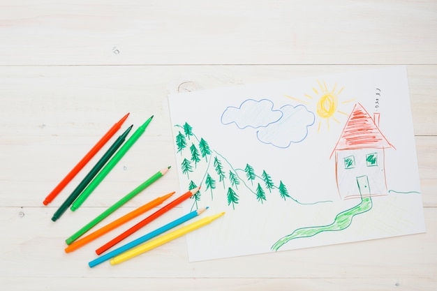Free Photo drawn painting on white sheet with colorful pencil over wooden textured