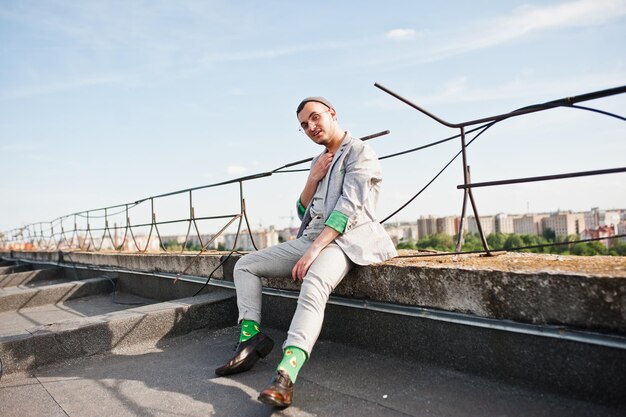 Dreamer stylish macho man in gray suit and glasses posed on the roof