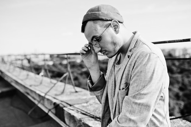 Free photo dreamer stylish macho man in gray suit hat and glasses posed on the roof