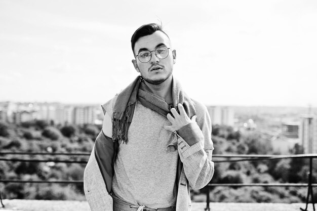 Dreamer stylish macho man in gray suit scarf and glasses posed on the roof