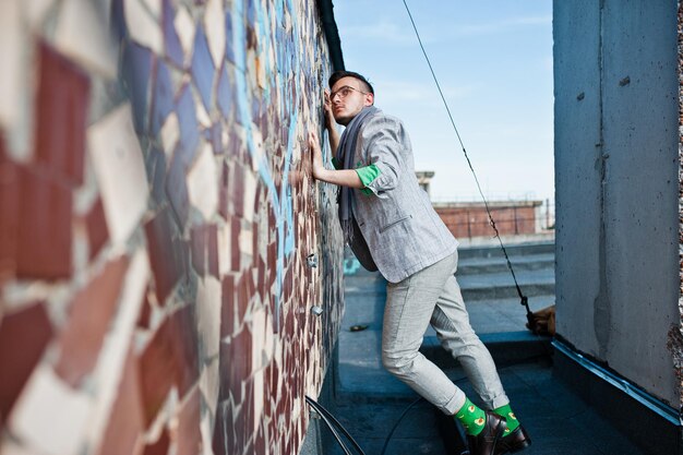 Free photo dreamer stylish macho man in gray suit scarf and glasses posed on the roof