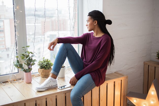 Dreamful African woman looking out window