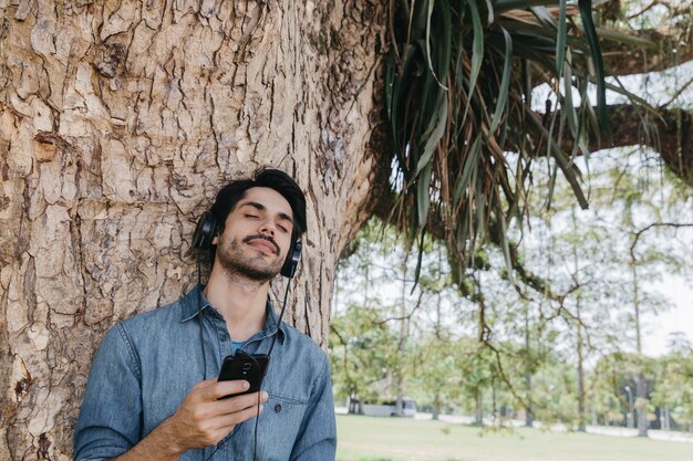 Dreaming man enjoying music in park