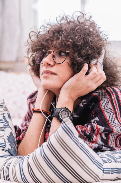 Free photo dreaming teenager listening to music on bed