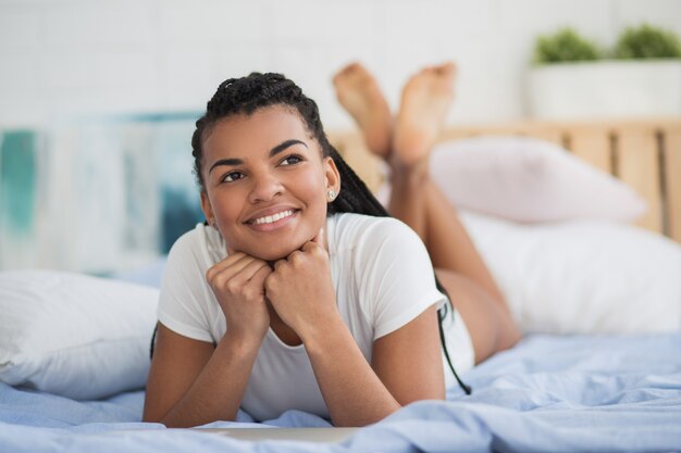 Dreamy African woman lying in bed