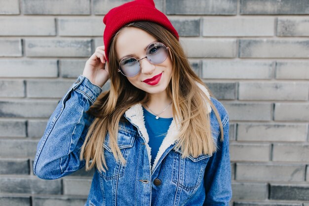 Dreamy caucasian woman in trendy clothes on brick wall