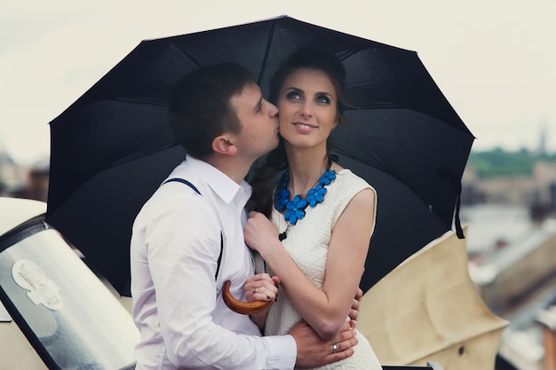 Free photo dreamy couple poses under umbrella on the roof