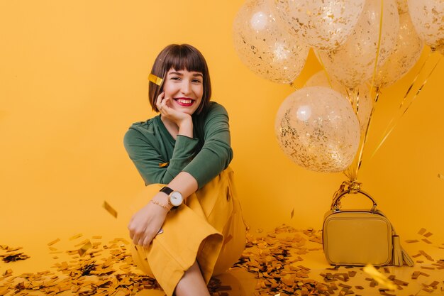 Dreamy girl in trendy wristwatch sitting. Portrait of romantic brunette woman enjoying birthday.