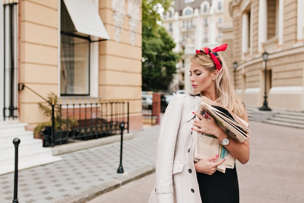 Dreamy girl with short blonde hair bought newspapers and going home to read it
