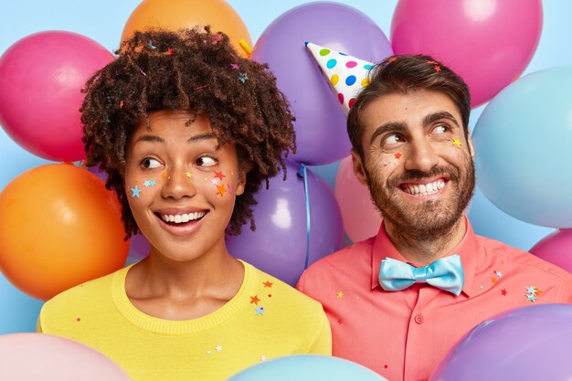 Dreamy glad young couple posing surrounded by birthday colorful balloons