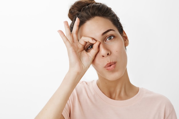 Foto gratuita ragazza felice vaga che posa contro il muro bianco