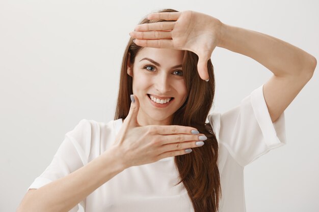 Dreamy happy woman making frames gesture, smiling cheerful