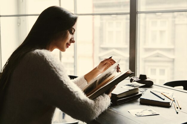 Dreamy lady sits with old photo-albums in the cafe